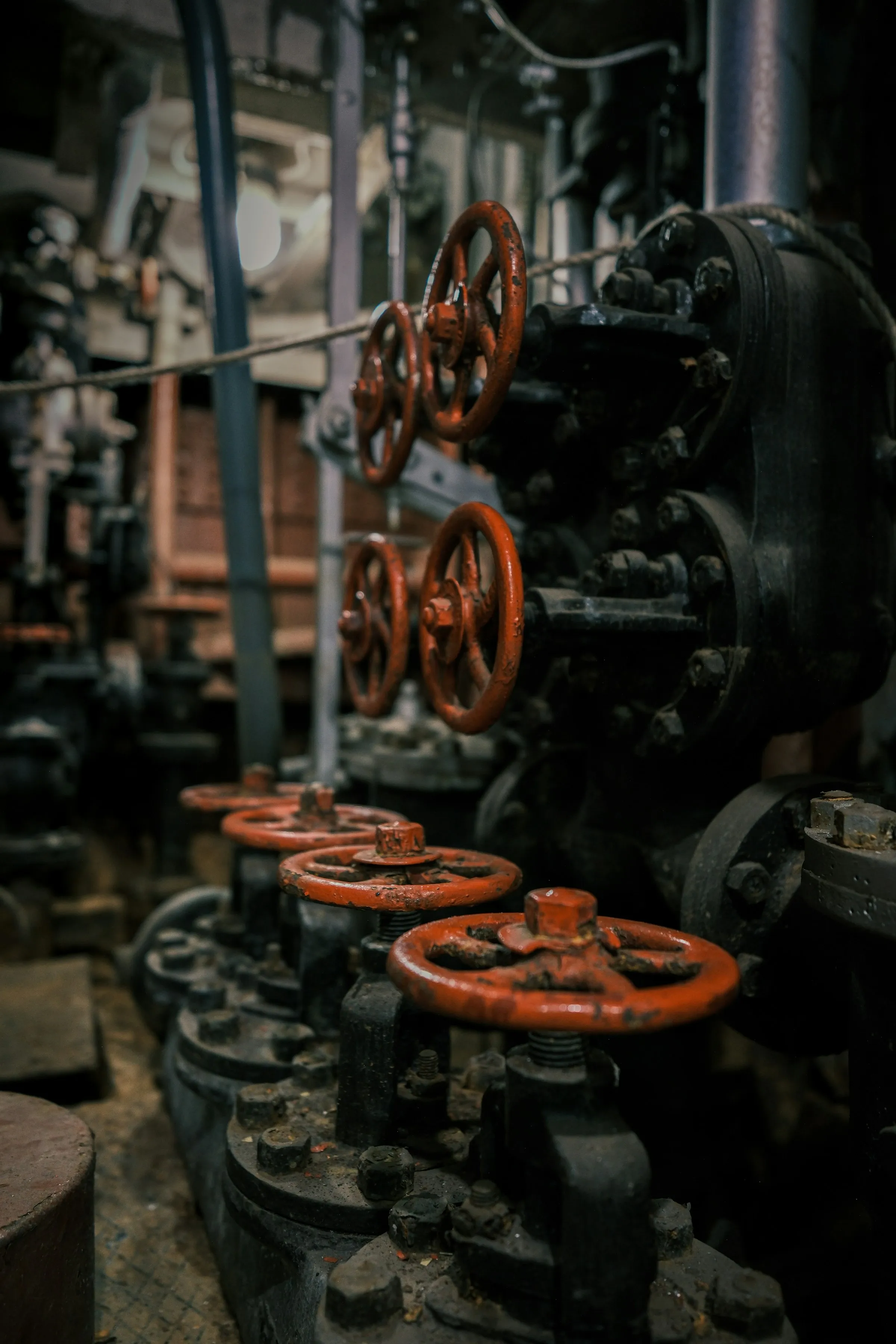 Válvulas industriales de una sala de máquinas en penumbra — el equipo físico que GLIDDER monitorea en tiempo real.
